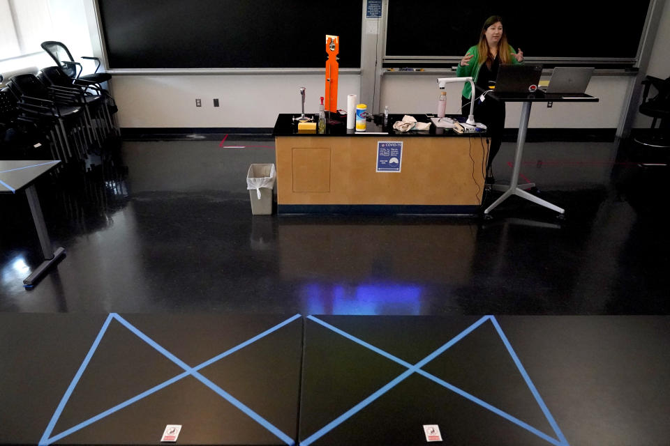 Sections of a table are seen blocked off with tape as assistant professor Jennifer Guerard speaks into laptops while teaching a foundations of chemistry remote class at the U.S. Naval Academy, Monday, Aug. 24, 2020, in Annapolis, Md. Under the siege of the coronavirus pandemic, classes have begun at the Naval Academy, the Air Force Academy and the U.S. Military Academy at West Point. But unlike at many colleges around the country, most students are on campus and many will attend classes in person. (AP Photo/Julio Cortez)