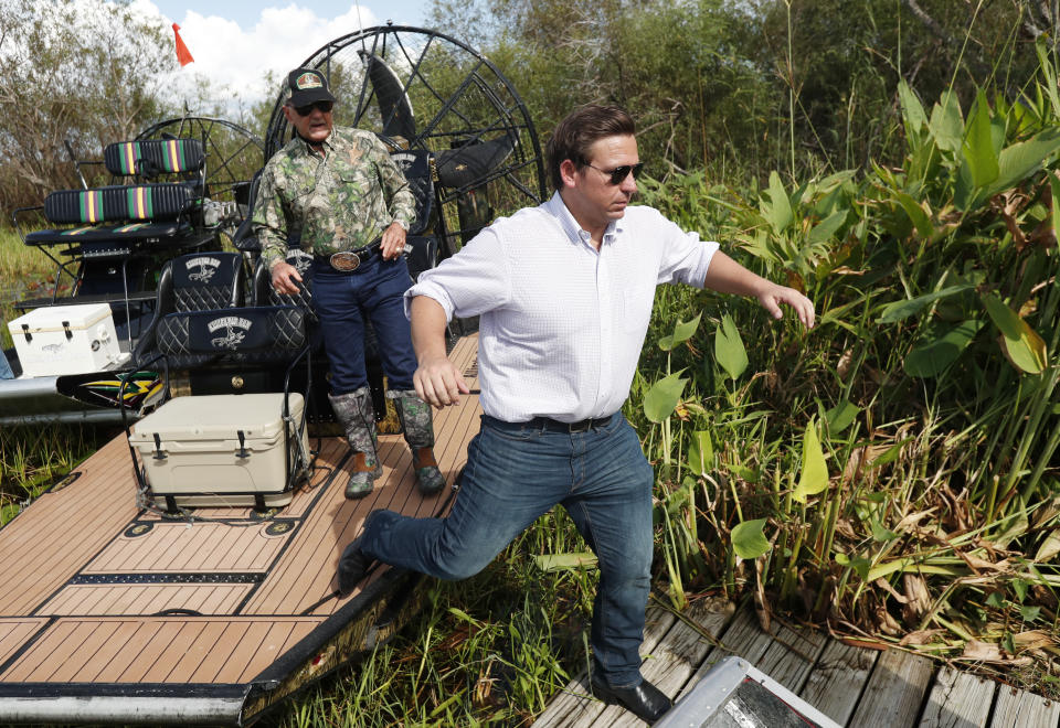 FILE - Then-Republican candidate for Florida Gov. Ron DeSantis, gets off an airboat with Gladesman and former Florida Fish and Wildlife Conservation commissioner Ron Bergeron after a tour of the Florida Everglades in Fort Lauderdale, Fla., Sept. 12, 2018. (AP Photo/Wilfredo Lee, File)