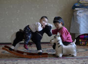 Kanat Kaliyev's son Adilet's daughters Aibike, right, and Aima play at the family house in Tash Bashat village, about 24 kilometers (15 miles) southeast of Bishkek, Kyrgyzstan, Saturday, Oct. 17, 2020. Political turmoil has gripped Kyrgyzstan over recent years, but life in this quiet village nestled between scenic mountains follows its centuries-old course.(AP Photo/Vladimir Voronin)