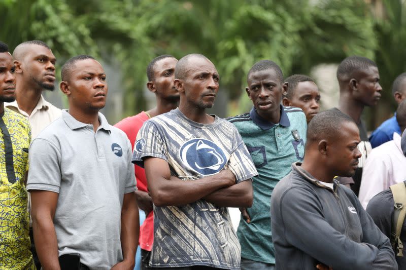 People gather outside as rescue workers continue to conduct search and rescue effort at the site of a collapsed building in Ikoyi