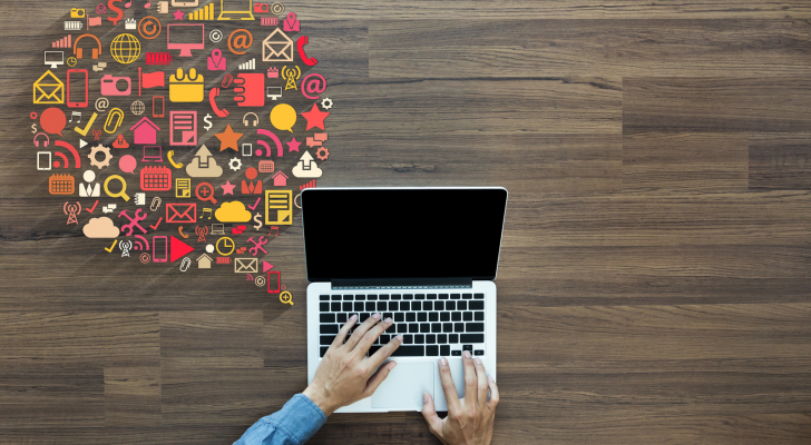 a photo of someone typing on a laptop on a wooden table with computer-related images