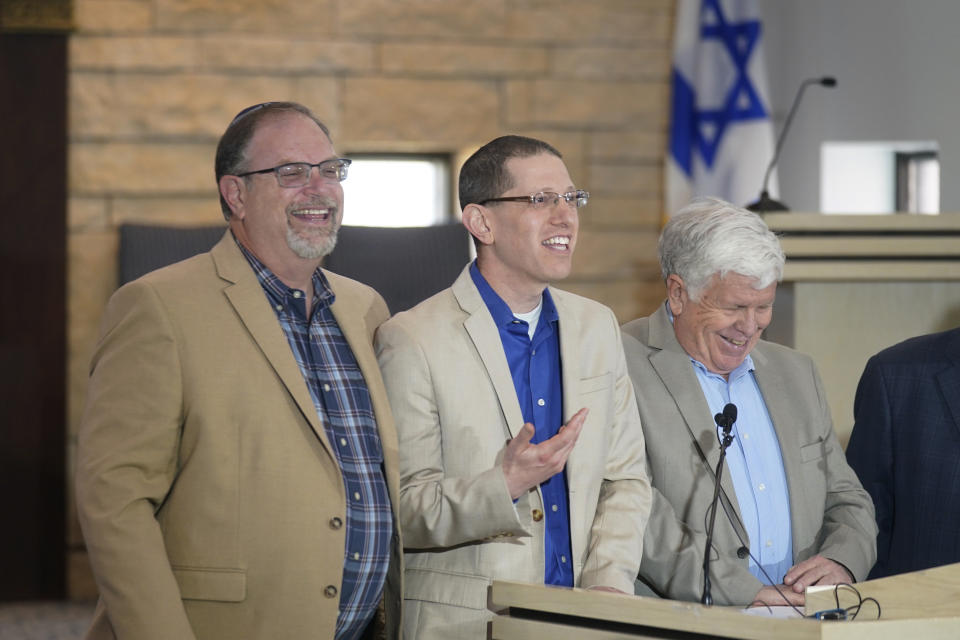 Michael Finfer, right, president of Congregation Beth Israel, laughs with Rabbi Charlie Cytron-Walker, center, and Jeff Cohen while speaking to reporters at the synagogue in Colleyville, Texas, Thursday, April 7, 2022. Three months after an armed captor took the three men hostage at the synagogue, the house of worship is reopening. (AP Photo/LM Otero)