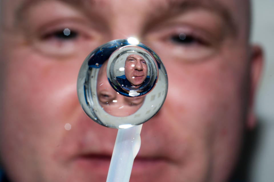 A water droplet in microgravity with a person behind it.