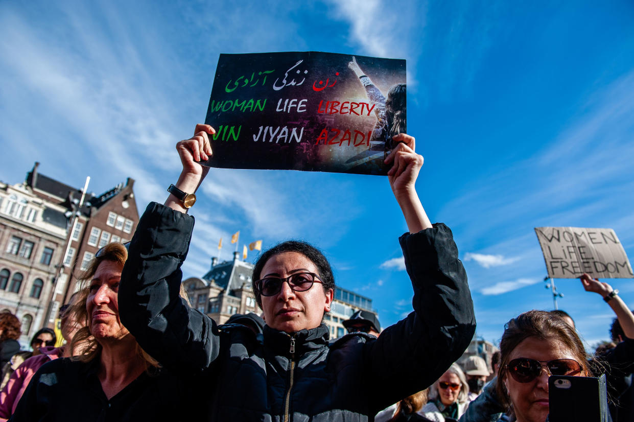 An Iranian woman is seen holding a placard with the three words that have become a symbol of protests, in Amsterdam on Oct. 16, 2022.
