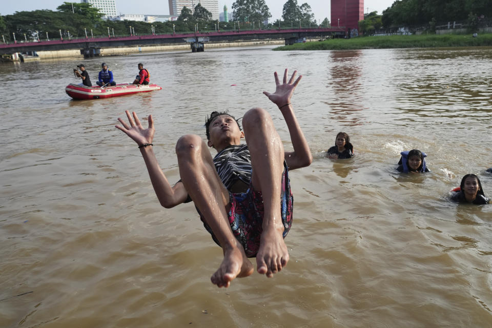 A man jumps into the Cisadane River, ahead the holy fasting month of Ramadan in Tangerang, Indonesia, Tuesday, March 21, 2023. Muslims followed local tradition to wash in the river to symbolically cleanse their soul prior to entering the holiest month in Islamic calendar. (AP Photo/Tatan Syuflana)