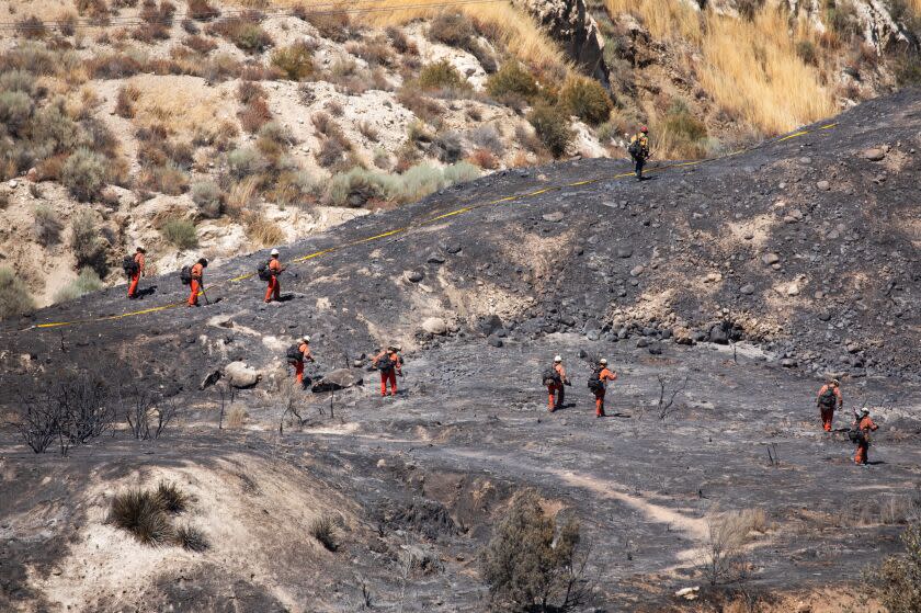 SANTA CLARITA, CA - JULY 26: A fire crew walks through a charred field at the Agua fire in north Los Angeles County on Wednesday, July 26, 2023. The fire burned more than 400 acres into the Angeles National Forest. (Myung J. Chun / Los Angeles Times)