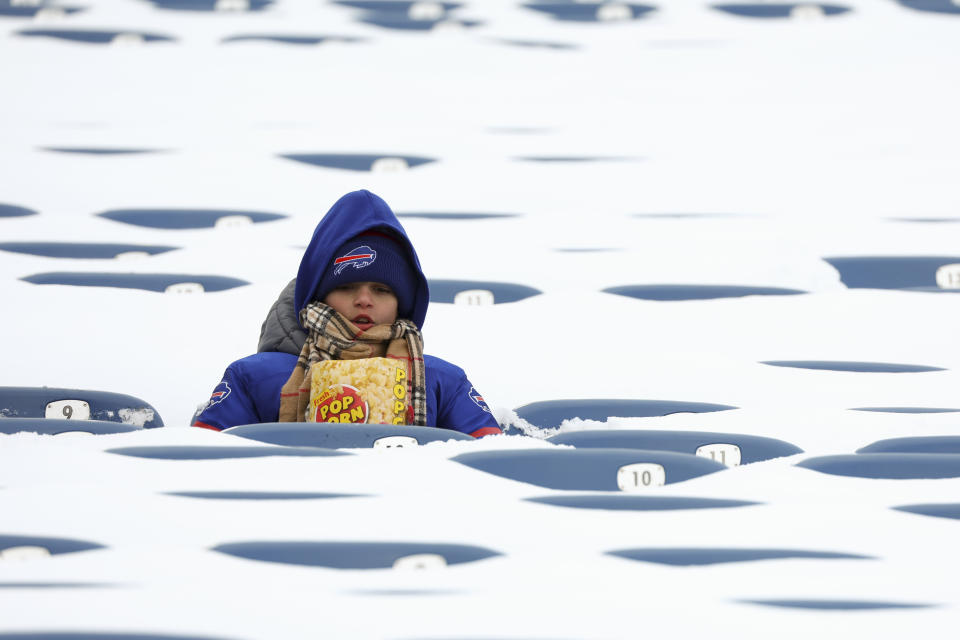 A young fan eats popcorn amid snow covered seats while waiting for the game to start.