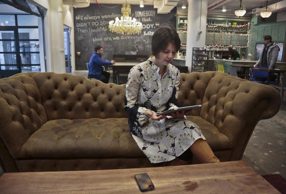 Jessica Wilt checks her work tablet as she sits in shared office and meeting space, Wednesday March 12, 2014 in New York. Wilt, 37, a former professional tap dancer who has freelance jobs managing a children’s dance program and arts grant programs, thought premiums would be too costly, but went back and found she had erred in projecting her 2014 earnings, and qualified for a much bigger subsidy. (AP Photo/Bebeto Matthews)