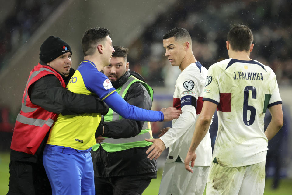 Portugal's Cristiano Ronaldo, second right, looks on as stewards remove a pitch invader during the Euro 2024 group J qualifying soccer match between Luxembourg and Portugal at the Stade de Luxembourg in Luxembourg, Sunday, March 26, 2023. (AP Photo/Olivier Matthys)