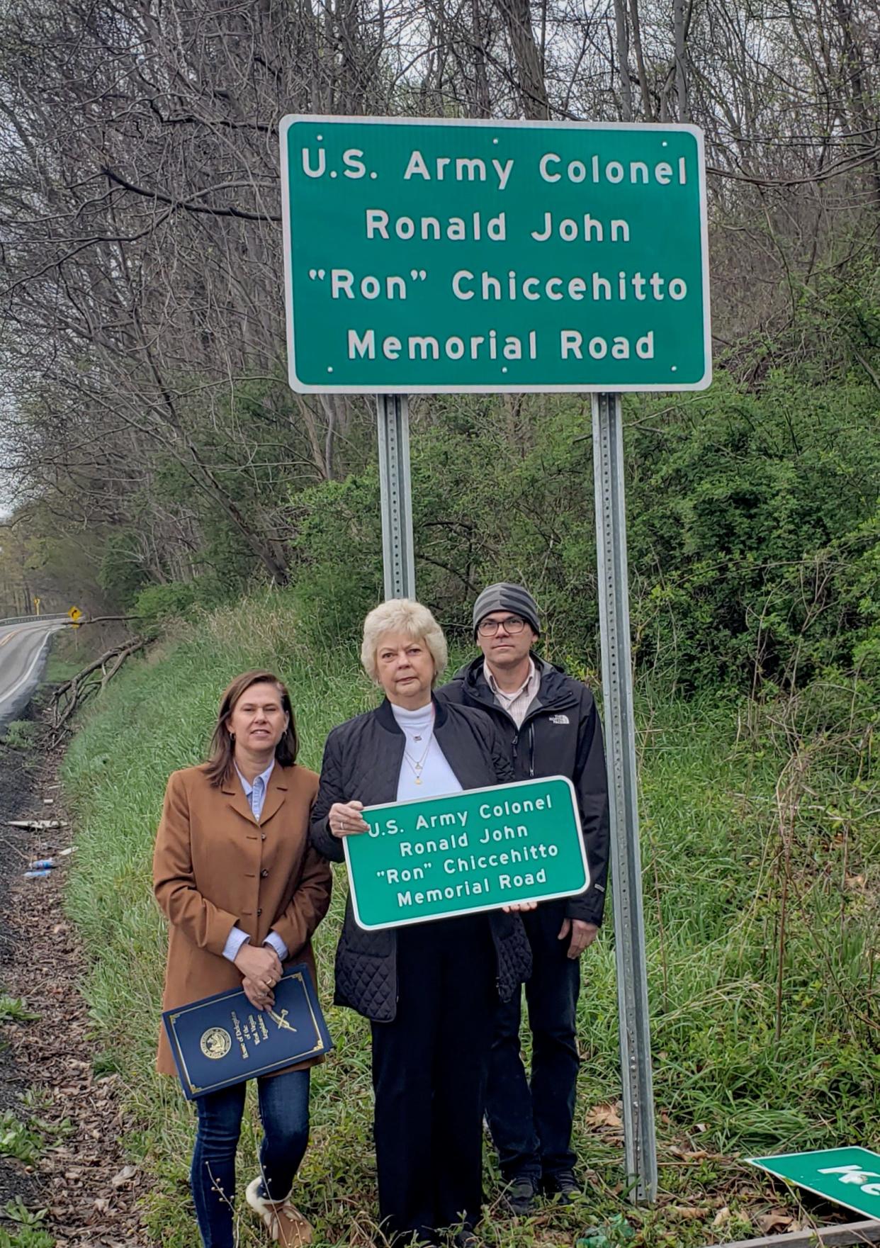 Daughter Dina Nelson, wife Jan Chiccehitto, and son  Louis Chiccehitto stand beneath the sign dedicating a portion of Route 46 in memory of Col. Ronald John “Ron” Chiccehitto.