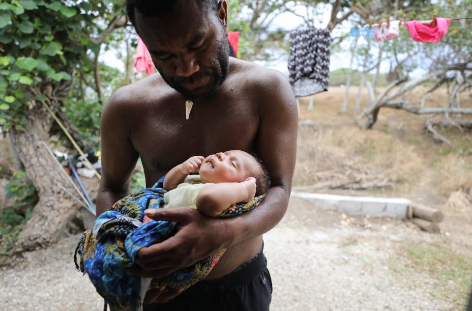 Albea Watt holds his baby son Tanny outside his home, which was destroyed by Cyclone Pam and rebuilt, on December 05, 2019 in Tanna, Vanuatu.