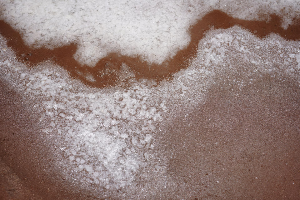 Salt begins to form in one of many salt beds in the Hanapepe salt patch on Friday, July 14, 2023, in Hanapepe, Hawaii. This Native Hawaiian salt has been hand made for generations and is one of the last remaining salt patches in all of Hawaii. (AP Photo/Jessie Wardarski)