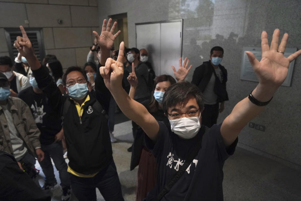 Protesters gesture with five fingers, signifying the "Five demands - not one less" outside a court in Hong Kong Friday, April 16, 2021. Seven of Hong Kong’s leading pro-democracy advocates, including 82-year-old veteran activist Martin Lee and pro-democracy media tycoon Jimmy Lai, are expected to be sentenced Friday for organizing a march during the 2019 anti-government protests that triggered an overwhelming crackdown from Beijing. (AP Photo/Kin Cheung)