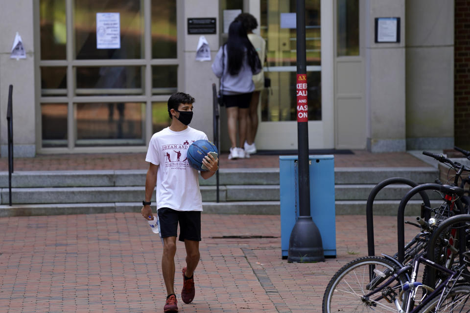 Students are seen outside Hinton James dormitory at the University of North Carolina in Chapel Hill, N.C., Tuesday, Aug. 18, 2020. The university announced that it would cancel all in-person undergraduate learning starting on Wednesday following a cluster of COVID-19 cases on campus. (AP Photo/Gerry Broome)