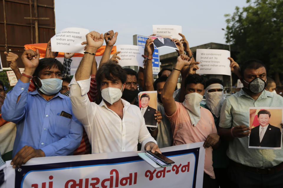 Indians shout slogans against China during a protest in Ahmedabad, India, Tuesday, June 16, 2020. At least three Indian soldiers, including a senior army officer, were killed in a confrontation with Chinese troops along their disputed border high in the Himalayas where thousands of soldiers on both sides have been facing off for over a month, the Indian army said Tuesday. Banner in Gujrati reads, "All Indians with Indian army and Indian government".(AP Photo/Ajit Solanki)