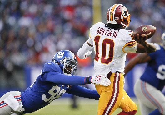 Washington Redskins quarterback Robert Griffin III (10) throws under pressure from New York Giants defensive end Damontre Moore (98) during the second quarter of an NFL football game, Sunday, Dec. 14, 2014, in East Rutherford, N.J. (AP Photo/Julio Cortez)