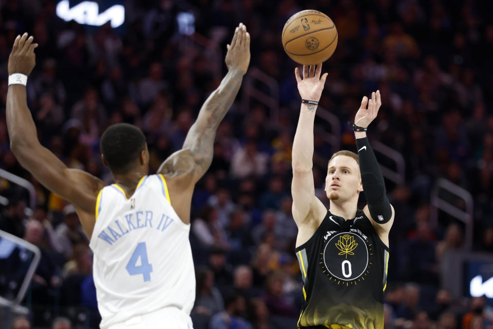 Golden State Warriors guard Donte DiVincenzo (0) shoots against Los Angeles Lakers guard Lonnie Walker IV (4) during the first half of an NBA basketball game in San Francisco, Saturday, Feb. 11, 2023. (AP Photo/Jed Jacobsohn)