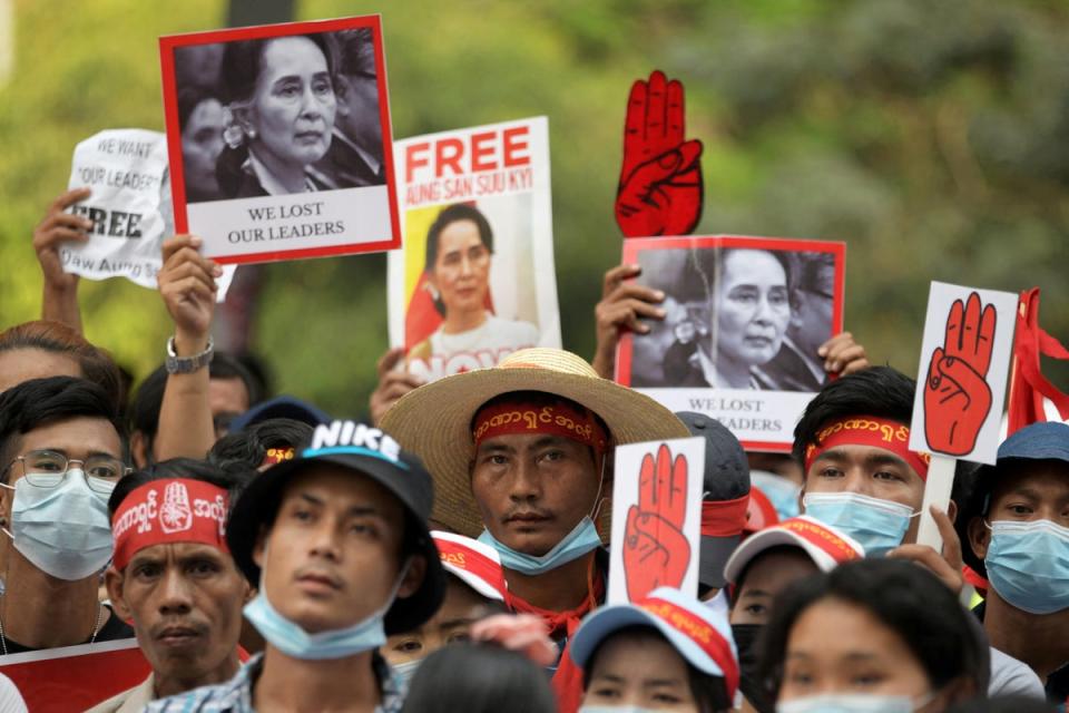 Demonstrators hold placards with pictures of Aung San Suu Kyi as they protest against the military coup in Yangon (REUTERS)
