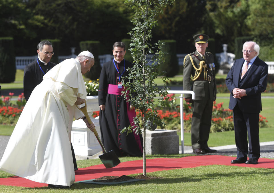 Pope Francis plants a tree during a meeting with Irish President Michael D Higgins, right, at Aras an Uachtarain in Phoenix Park, Dublin, Ireland, Saturday, Aug. 25, 2018. Pope Francis is on a two-day visit to Ireland. (Joe Giddens/PA via AP)