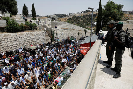 FILE PHOTO: Israeli border police officers stand guard as Palestinians pray at Lion's gate, an entrance to Jerusalem's Old City, in protest over Israel's new security measures at the compound housing al-Aqsa mosque, known to Muslims as Noble Sanctuary and to Jews as Temple Mount July 20, 2017. REUTERS/Ronen Zvulun/File Photo