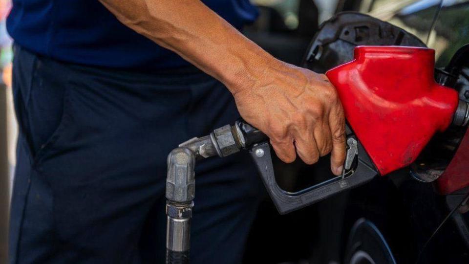 Hombre llenando un tanque de gasolina. 