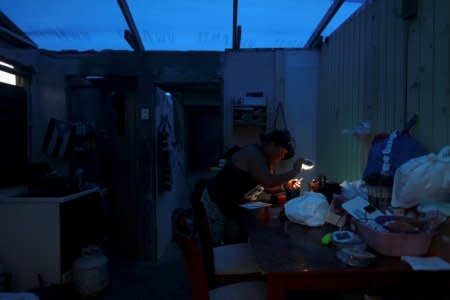 A woman uses a flashlight while trying to connect a transformer to a car battery, after Hurricane Maria hit the island in September 2017, in Maunabo, Puerto Rico January 27, 2018. Picture taken January 27, 2018. REUTERS/Alvin Baez