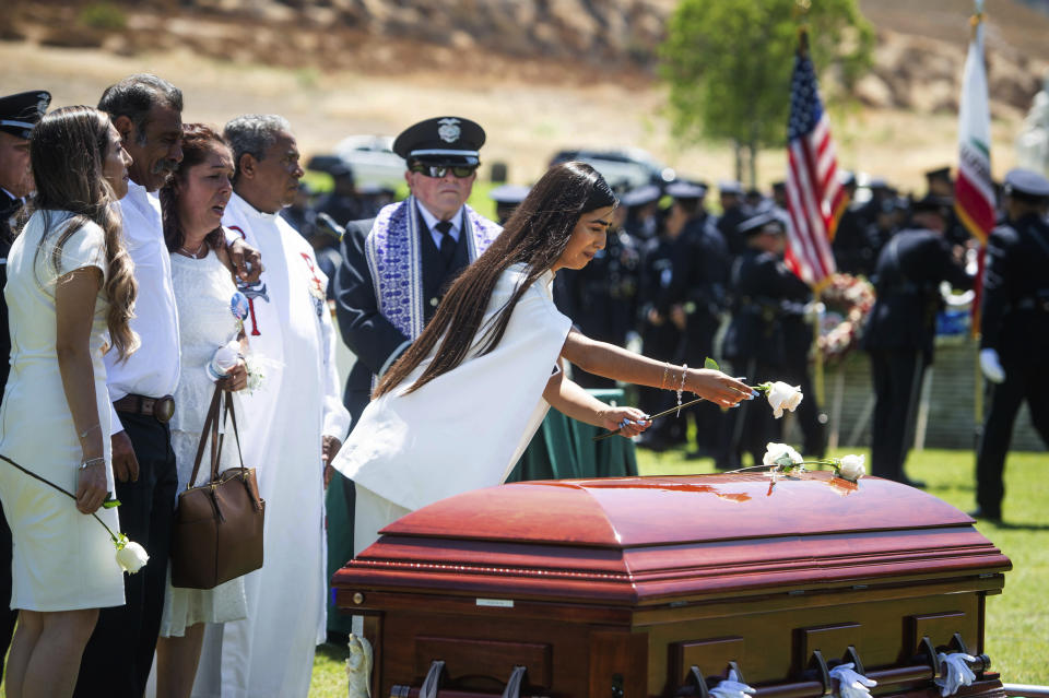 Anahi Diaz places a flower on her brother Los Angeles Police Department Officer Juan Jose Diaz's casket with her family during the funeral at Forest Lawn Hollywood Hills cemetery, Monday, Aug. 12, 2019, in Los Angeles. Juan Jose Diaz was killed while off duty in Lincoln Heights after visiting a taco stand. (Sarah Reingewirtz/The Orange County Register via AP)