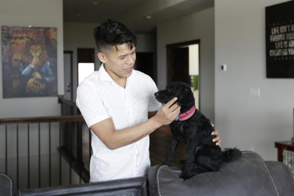 Jenderson Rondon, a Venezuelan humanitarian parole program beneficiary, plays with Michi, a dog owned by Dr. Kyle Varner, who is his program sponsor, at Varner's house, Friday, Jan. 6, 2023, in Spokane, Wash. (AP Photo/Young Kwak)