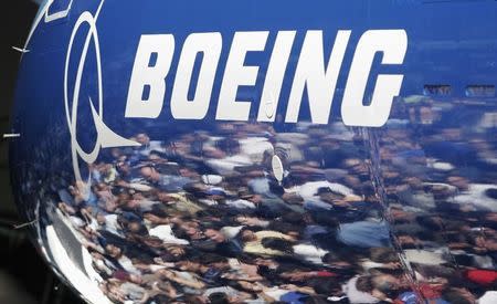 Invited guests for the world premiere of the Boeing 787 Dreamliner are reflected in the fuselage of the aircraft at the 787 assembly plant in Everett, Washington, July 8, 2007. REUTERS/Robert Sorbo