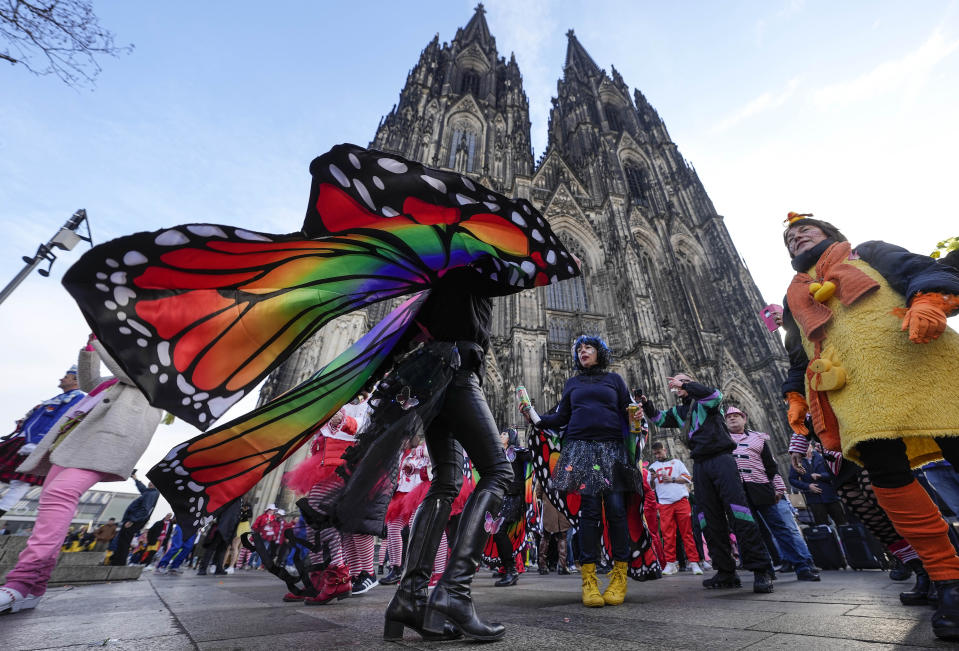 Vistiendo colores brillantes y disfraces creativos, juerguistas bailan al inicio del carnaval frente a la Catedral de Colonia, Alemania, el jueves 16 de febrero de 2023. (AP Foto/Martin Meissner)