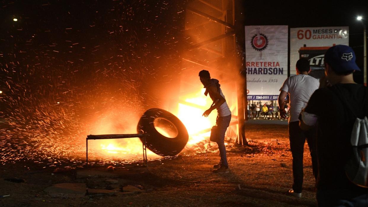 Ein Demonstrant wirft einen Reifen in ein Feuer, das von den Protestlern gelegt wurde. Foto: Carlos Herrera