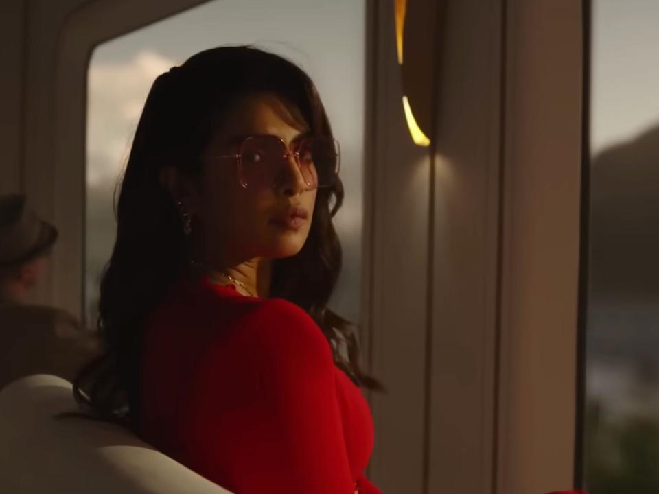 Priyanka Chopra in a red dress looking out the window of a train on "Citadel"