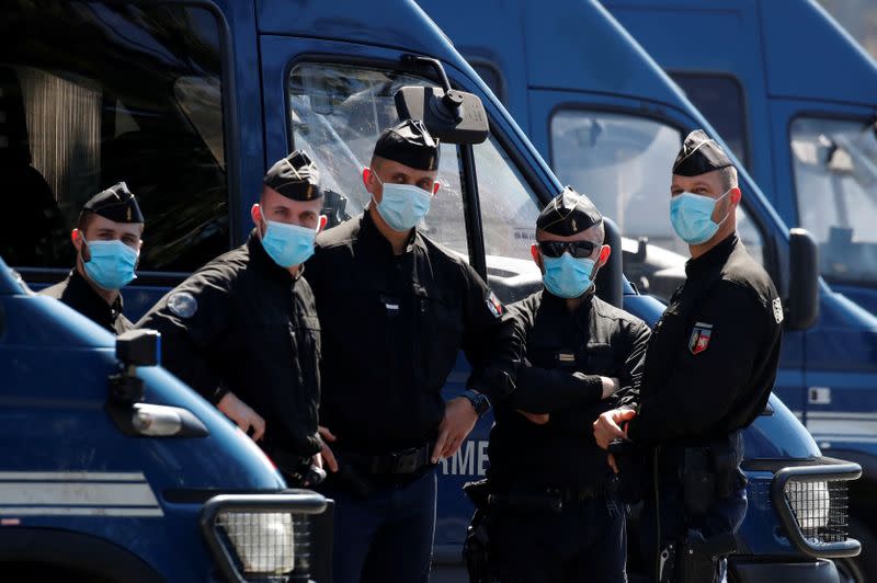 French Gendarmes wearing protective face masks stand in front of the Paris courthouse