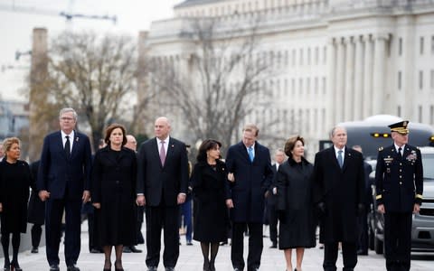 Former President George W Bush, former first lady Laura Bush, Neil Bush, Sharon Bush, Bobby Koch, Doro Koch, Jeb Bush and Columba Bush, stand just prior to the flag-draped casket - Credit: Reuters