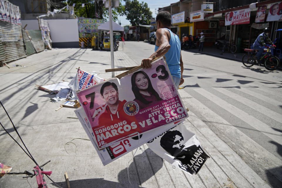 A village worker removes a campaign poster showing Presidential candidate Ferdinand "Bongbong" Marcos Jr., left, along a street in Quezon city, Philippines on Wednesday, May 11, 2022. Marcos, the namesake son of longtime dictator Ferdinand Marcos, apparent landslide victory in the Philippine presidential election is raising immediate concerns about a further erosion of democracy in Asia and could complicate American efforts to blunt growing Chinese influence and power in the Pacific. (AP Photo/Aaron Favila)