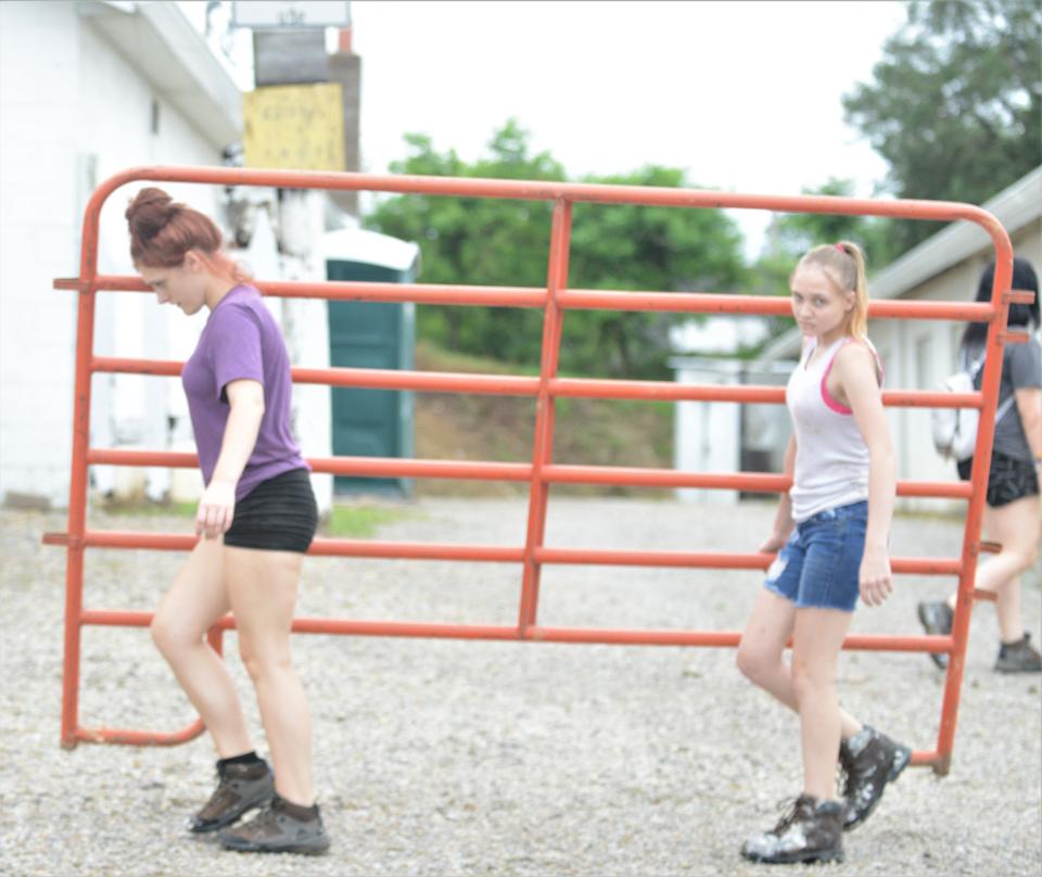 Foxfire High School students, Laila Snodgrass (left) and Alisha Smith, carry a gate for the stables at the Muskingum County Fairgrounds. They are taking part in a summer work program and helping to prepare the grounds for the fair in August.