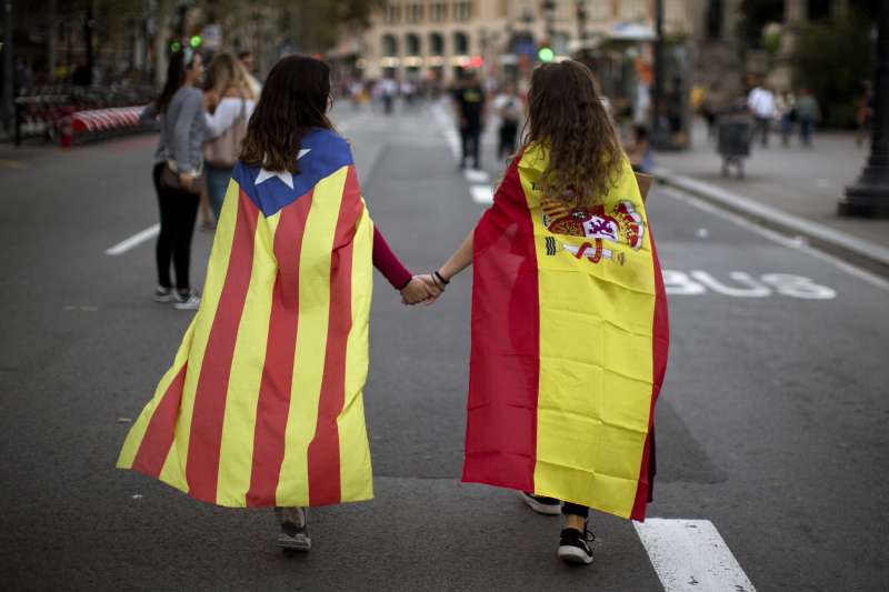 西班牙東北部加泰隆尼亞自治區獨立公投之後，與馬德里中央政府劍拔弩張，不過兩個各披著加泰隆尼亞孤星旗（左）與西班牙國旗的小女孩，還是可以牽手回家（AP）