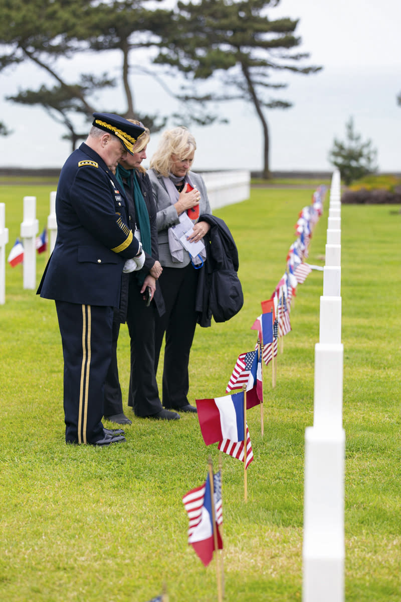 Associated Press reporter Tara Copp, center, stands with Joint Chiefs Chairman Gen. Mark Milley, left, and his wife Hollyanne as they pray over the Normandy American Cemetery gravesite of Pfc. Terry Harris, Copp's great-uncle, in Colleville-sur-Mer, Normandy, France, June 6, 2023. Copp was covering Milley's last trip to Normandy as a U.S. soldier. Milley has called his visits to Normandy to mark D-Day "spiritual." His father served at Iwo Jima as a Marine and his mother served as a nurse, and Milley served in both airborne divisions who jumped into Normandy on June 6, 1944. He also commanded the 506th Parachute Infantry Regiment, which was Harris' unit. (Oren Lieberman/CNN via AP)
