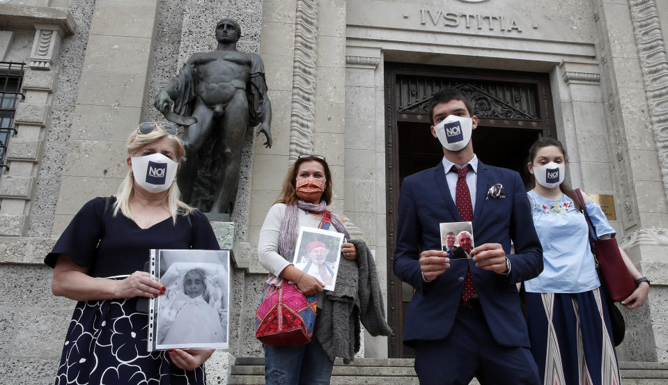 FILE - In this June 10, 2020 file photo, from left, Laura Capella, Nicoletta Bosica, Stefano Fusco and Arianna Dalba hold pictures of their relatives, victims of COVID-19, as they stand in front of Bergamo's courthouse, Italy. Italy is poised to reclaim the dishonor of reporting the most coronavirus deaths in Europe, as the second surge ravages the country’s disproportionately old population and exposes how public health shortfalls and delayed restrictions compounded a lack of preparedness going into the pandemic. (AP Photo/Antonio Calanni, file)