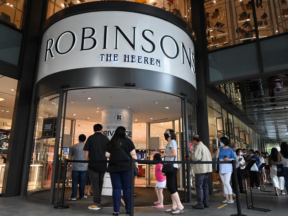 Customers queue to enter a Robinsons department store at the Hereen in the Orchard Road shopping belt in Singapore