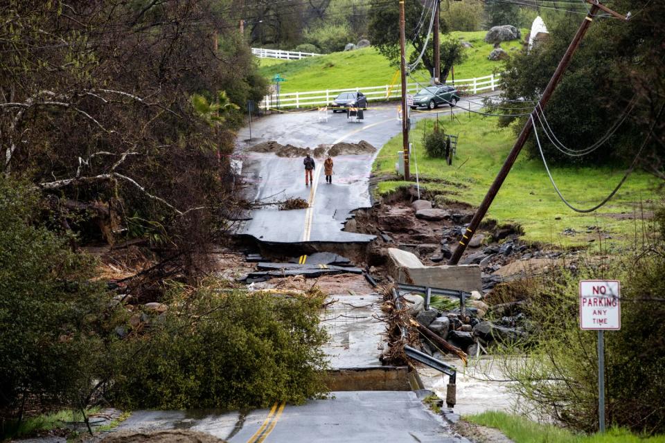 Residents check out a flood-damaged road