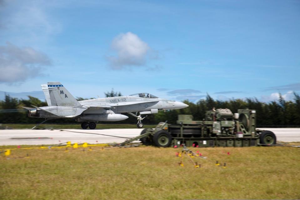 An F/A-18 Hornet lands on the runway to be stopped by an M-31 expeditionary arresting gear system at Tinian’s West Field during exercise Forager Fury II. The training consisted of rapid ground refueling and arrested landing operations, extending aviation training throughout the Mariana Island Range Complex. <em>U.S. Marine Photo by Lance Cpl. Antonio Rubio/Released</em> A USMC Hornet executes short-field recovery operations using a mobile arresting gear system on the island of Tinian. (U.S. Marine Photo by Lance Cpl. Antonio Rubio/Released)