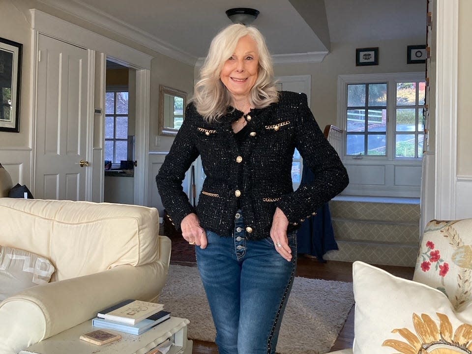 Donna Sasse in her living room wearing jeans and a black jacket.