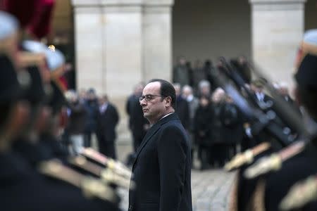 French President Francois Hollande stands in attention during a funeral ceremony honouring Robert Chambeiron, member of the Resistance during World War II (WWII), at the Hotel des Invalides in Paris, January 8, 2015. REUTERS/Etienne Laurent/Pool