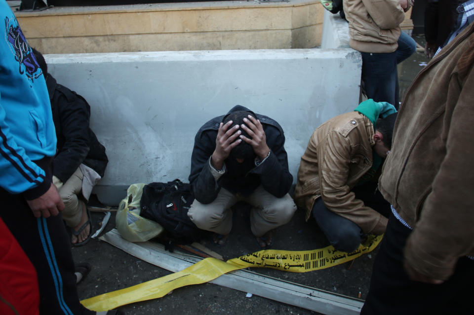 Egyptian police officers sit on the street after a blast at the Egyptian police headquarters in downtown Cairo, Friday, Jan. 24, 2014. A car bomb struck the Egyptian police headquarters in downtown Cairo on Friday, killing at least several people and wounding dozens, the country's state media reported. (AP Photo/Khalil Hamra)