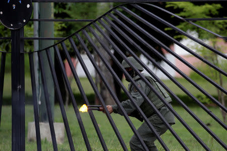 A riot security officer fires rubber bullets at demonstrators as they rally against Venezuela's President Nicolas Maduro in Caracas, Venezuela. REUTERS/Marco Bello