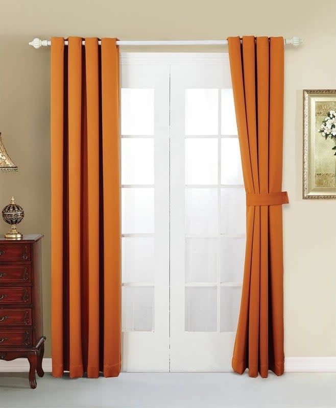 A set of orange curtains tied back on a window