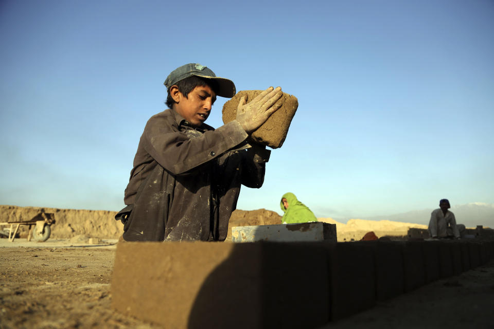 In this Wednesday, June 19, 2019, photo, Kamran, 10, works at a brick factory on the outskirts of Kabul, Afghanistan. Every day before dawn, 10-year-old Kamran goes to work with his father and other relatives at a brick factory on the outskirts of Kabul. Like many children in Afghanistan, school is a luxury his family can no longer afford. His father, Atiqullah, supports his family of eight as well as several siblings, nieces and nephews.(AP Photo/Rahmat Gul)