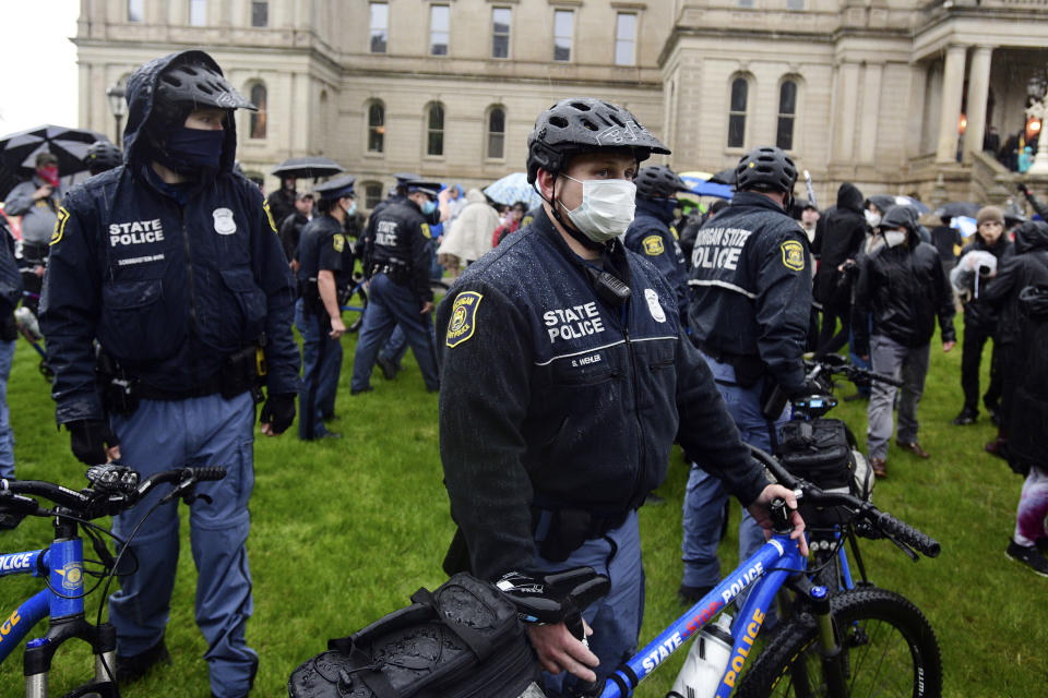 Michigan State Police surround a man after skirmish broke out between protestors as a man with a flag that had doll with a noose around its neck came to the front of the stage during a protest against the state's stay-at-home order at the Michigan Capitol in Lansing on Thursday, May 14, 2020. ( J. Scott Park/Jackson Citizen Patriot via AP)