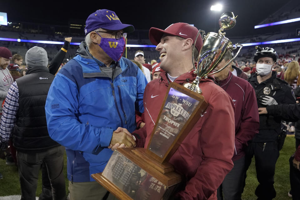 Washington State acting head coach Jake Dickert, right shakes hands with Washington Gov. Jay Inslee, left, after Inslee presented him with the Apple Cup Trophy after Washington State beat Washington 40-13 in an NCAA college football game, Friday, Nov. 26, 2021, in Seattle. (AP Photo/Ted S. Warren)